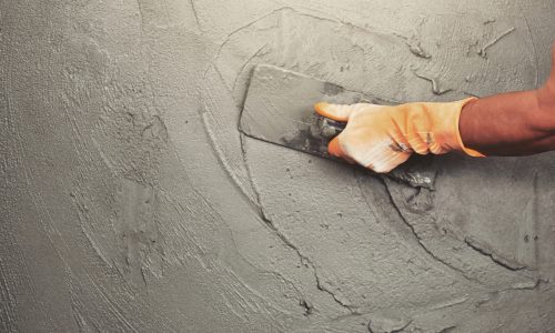 hand of worker plastering cement at wall for building house